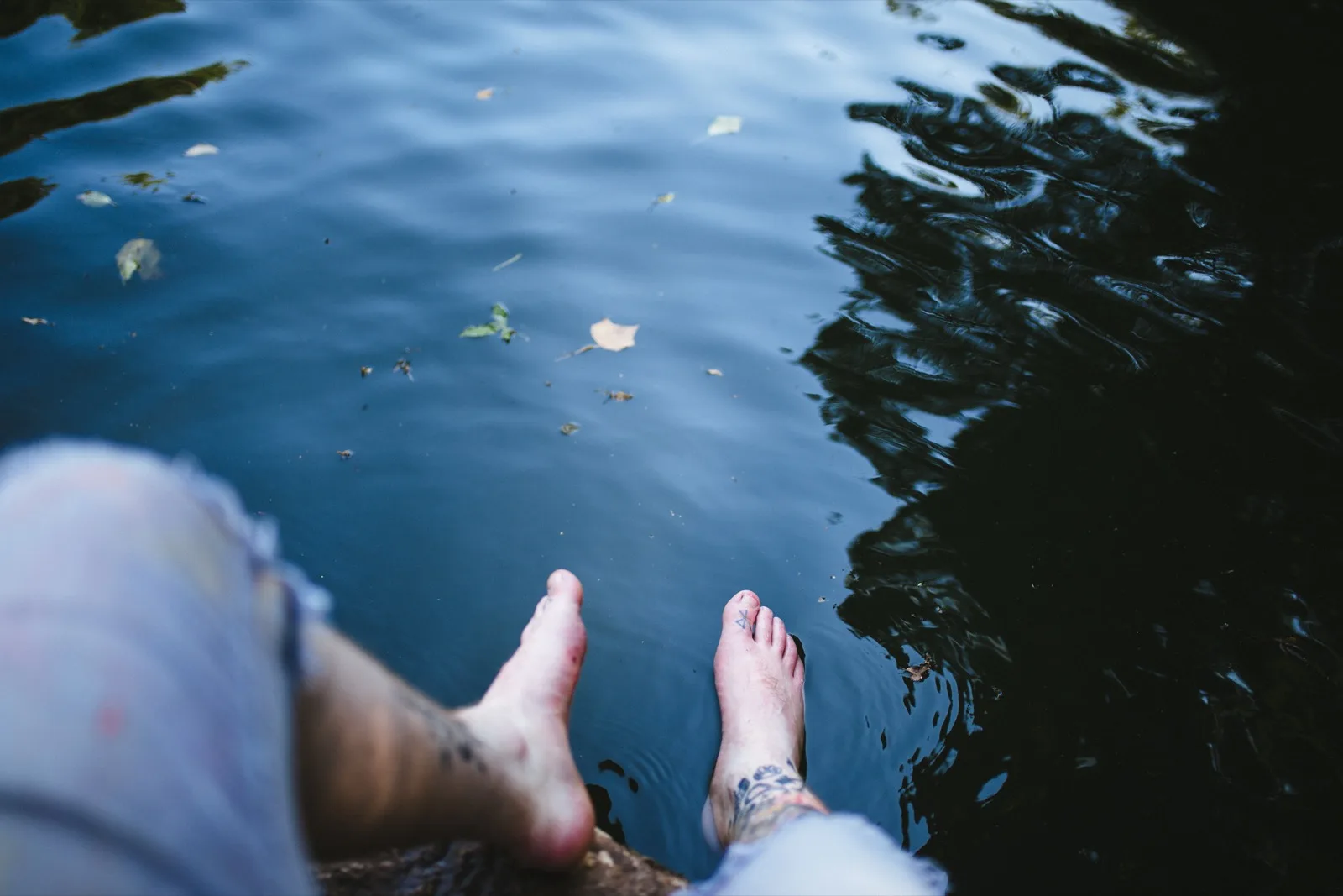 A person resting their feet on a pool edge at sunset — a symbol of light, comfortable legs